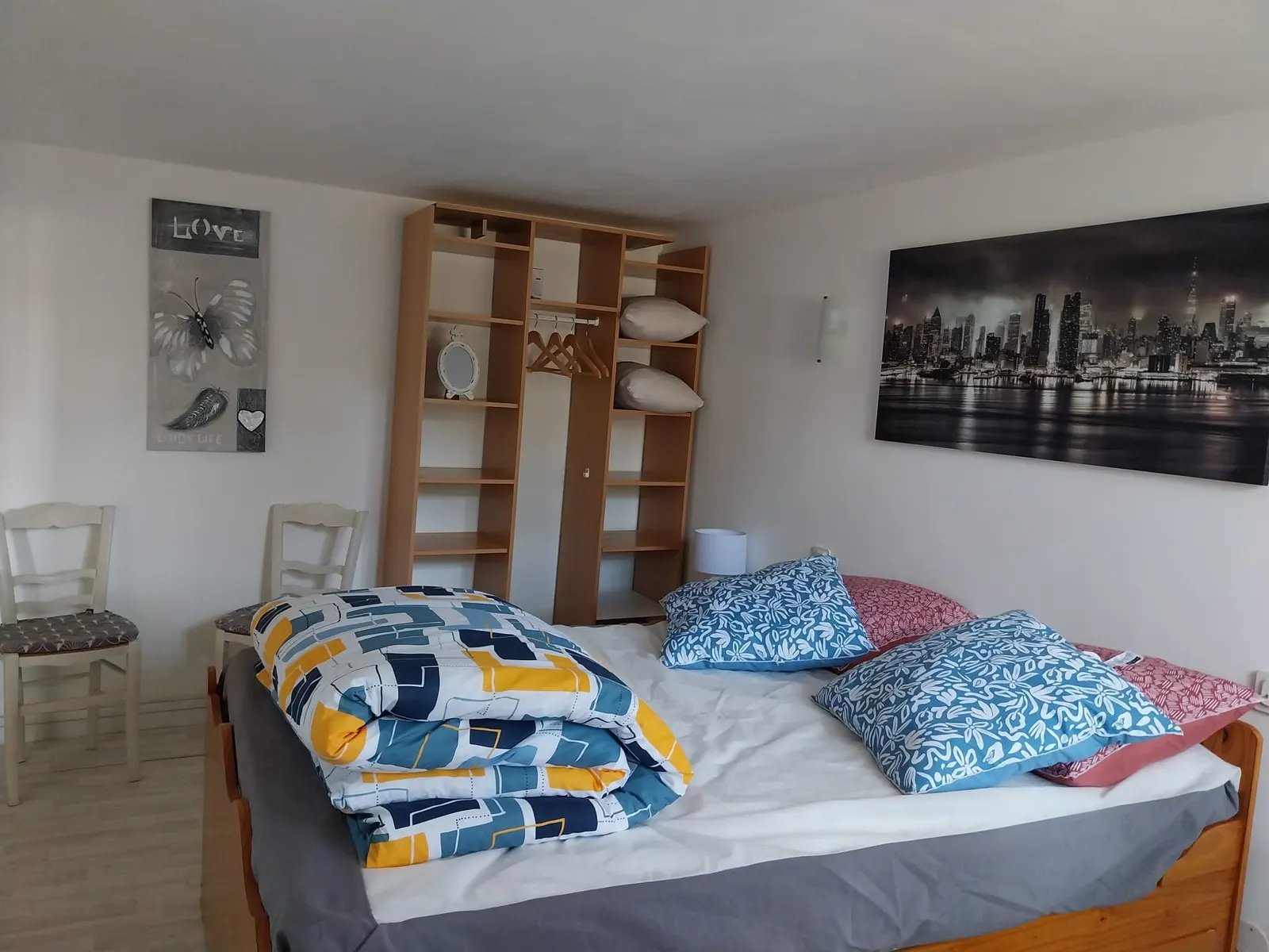 Chambre avec lit double, coussins bleus et panneau lumineux « Le Répit » — vue 2