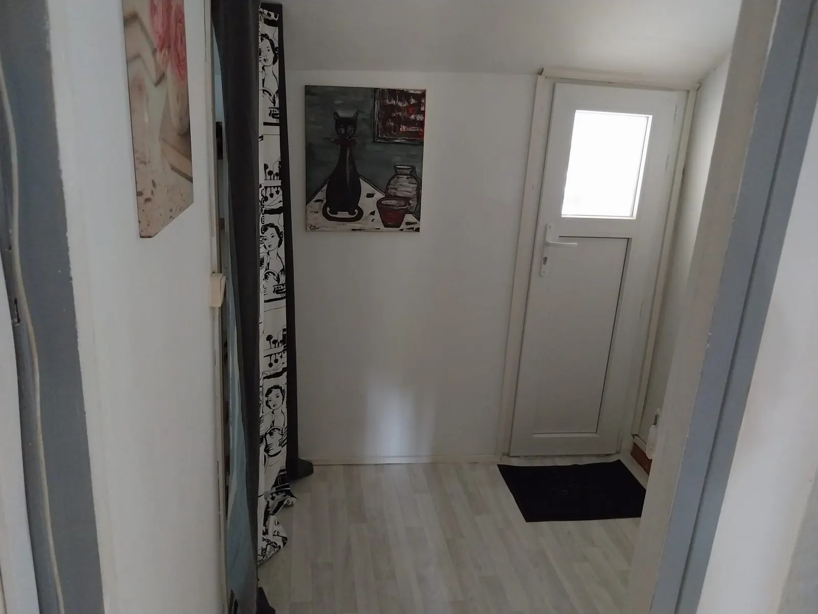 L'entrée du Répit : porte vitrée, tableaux et paillasson